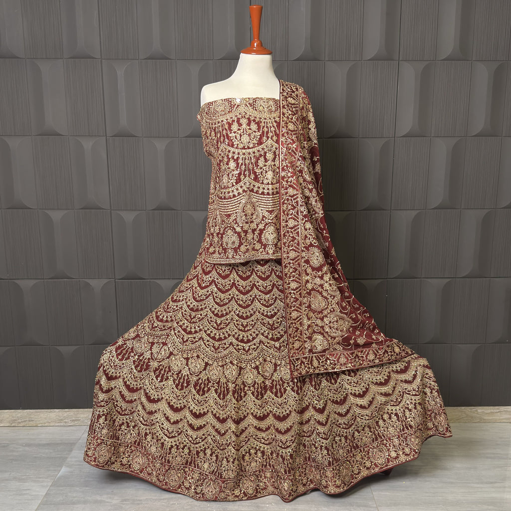 Traditional embroidered outfit on a mannequin against a textured gray wall BRIDAL LEHENGA INDIAN MACHINE WORKI N PAKISTAN PRICE