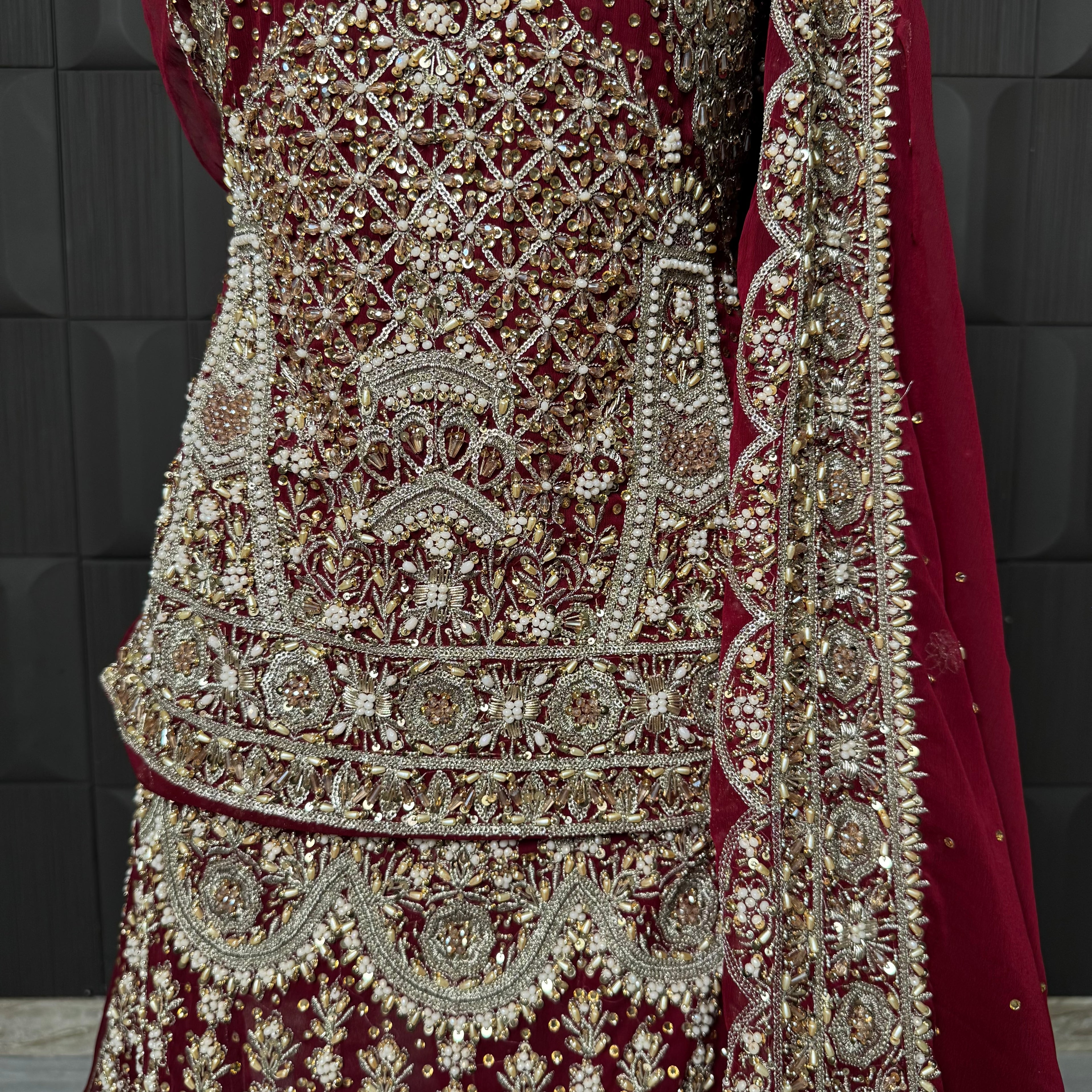 Wedding lehenga hand work close-up showing kora dabka jewelry material embroidery on red chiffon fabric