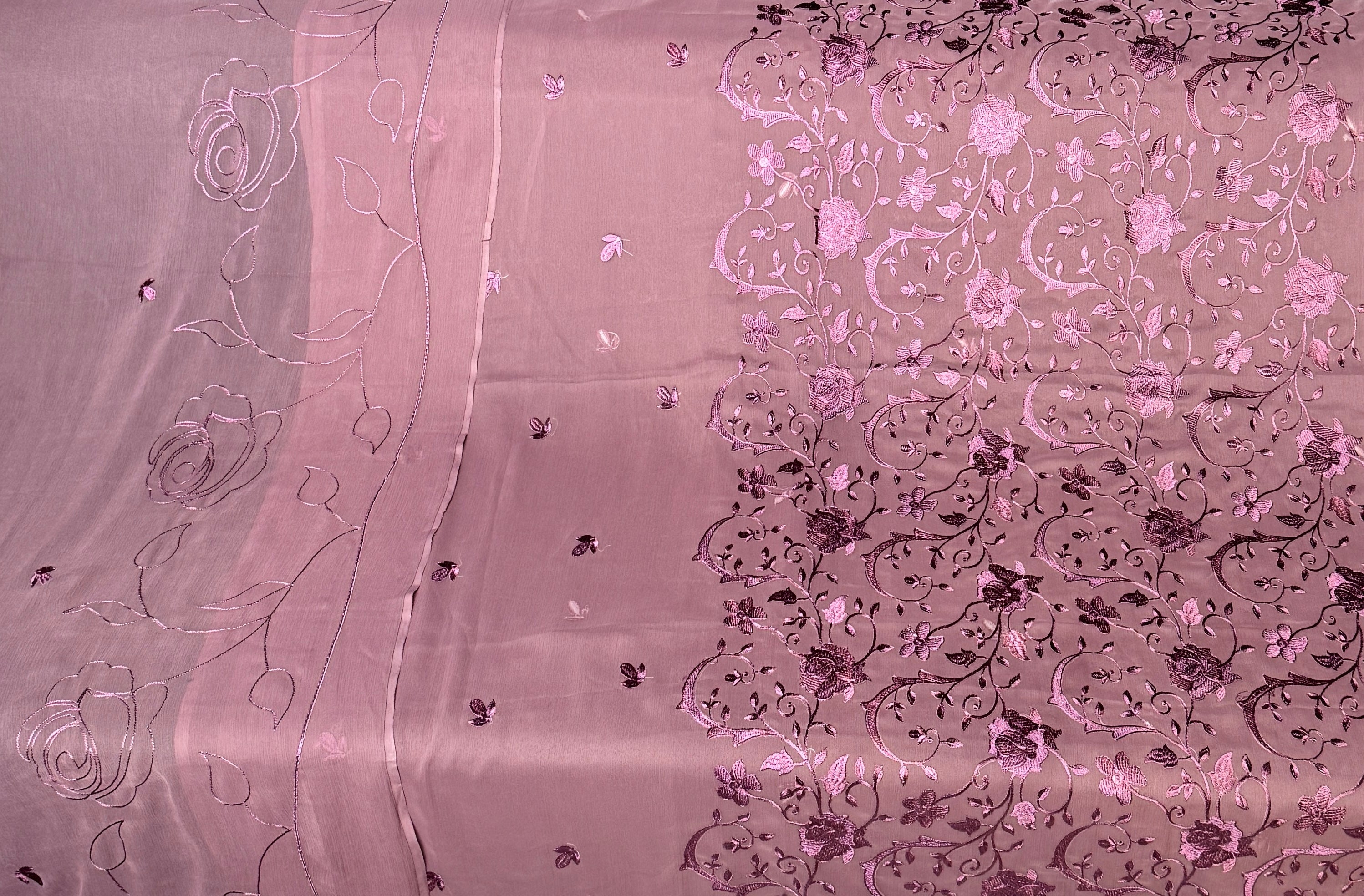A close-up of a pink sheer fabric with metallic silver floral embroidery and sequins, showing both the plain and patterned sides.