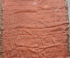 A square peach-colored fabric scarf or shawl with metallic gold embroidered details and a gold border, laid flat on a gray tiled floor.
