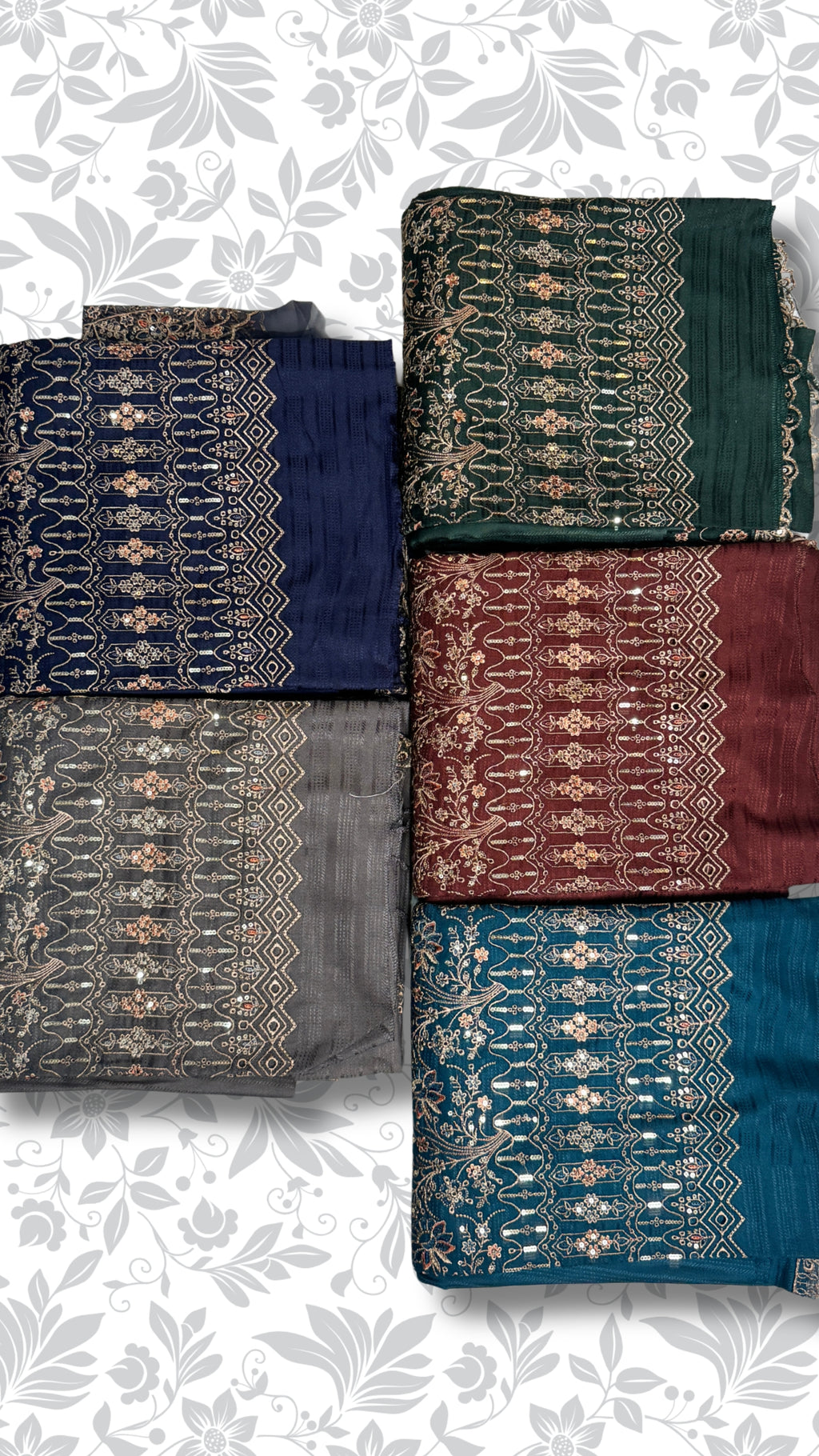 Six folded fabric pieces with ornate metallic embroidery arranged in two columns on a white background with a light gray floral pattern. The fabrics are in dark green, navy blue, charcoal gray, burgundy red, and teal blue.