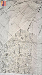 A light beige or off-white fabric garment laid flat, featuring delicate floral embroidery and a decorative border. The fabric has a warm, slightly cream undertone, which maps best to Beige in the allowed color palette.