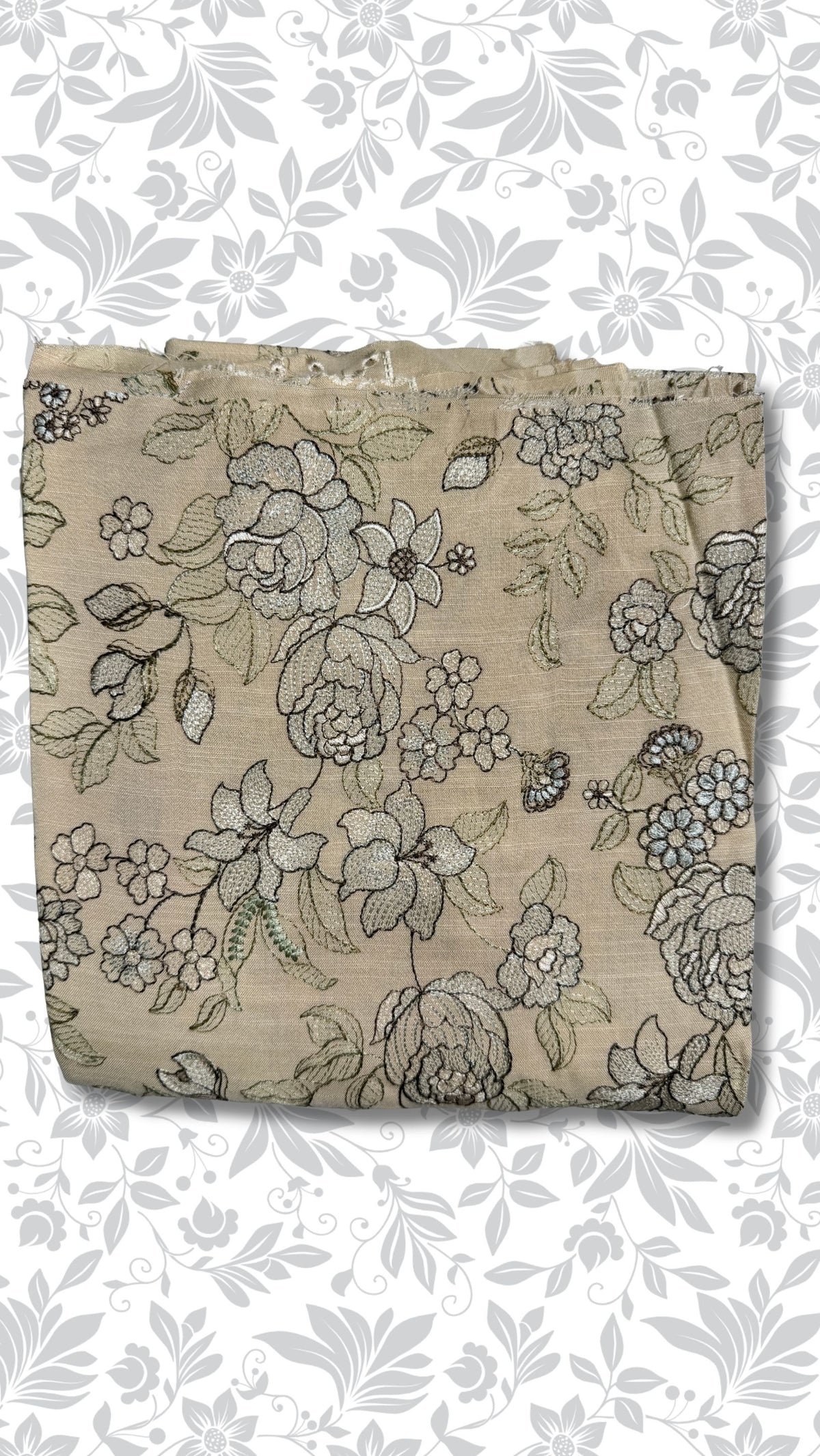 A folded piece of beige fabric with a detailed black and gray floral print, displayed against a white background with a gray floral pattern.