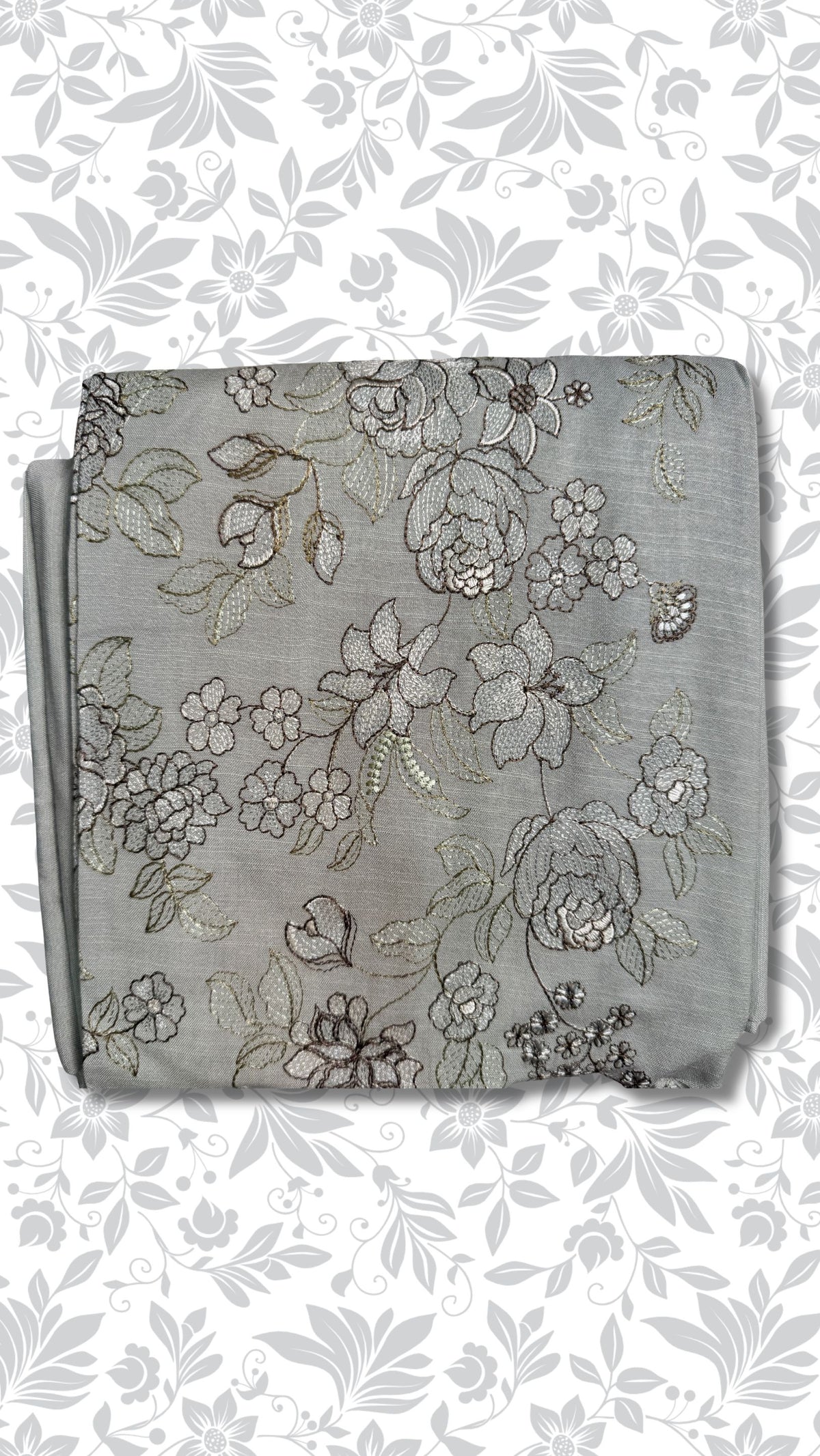 A folded piece of light gray fabric with intricate silver and gold floral embroidery, displayed on a white background with a gray floral pattern.