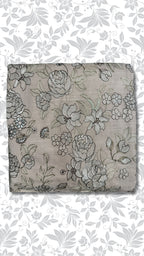 A folded piece of taupe fabric featuring an intricate black and gray floral embroidery pattern, presented against a white background with a matching gray floral watermark overlay.