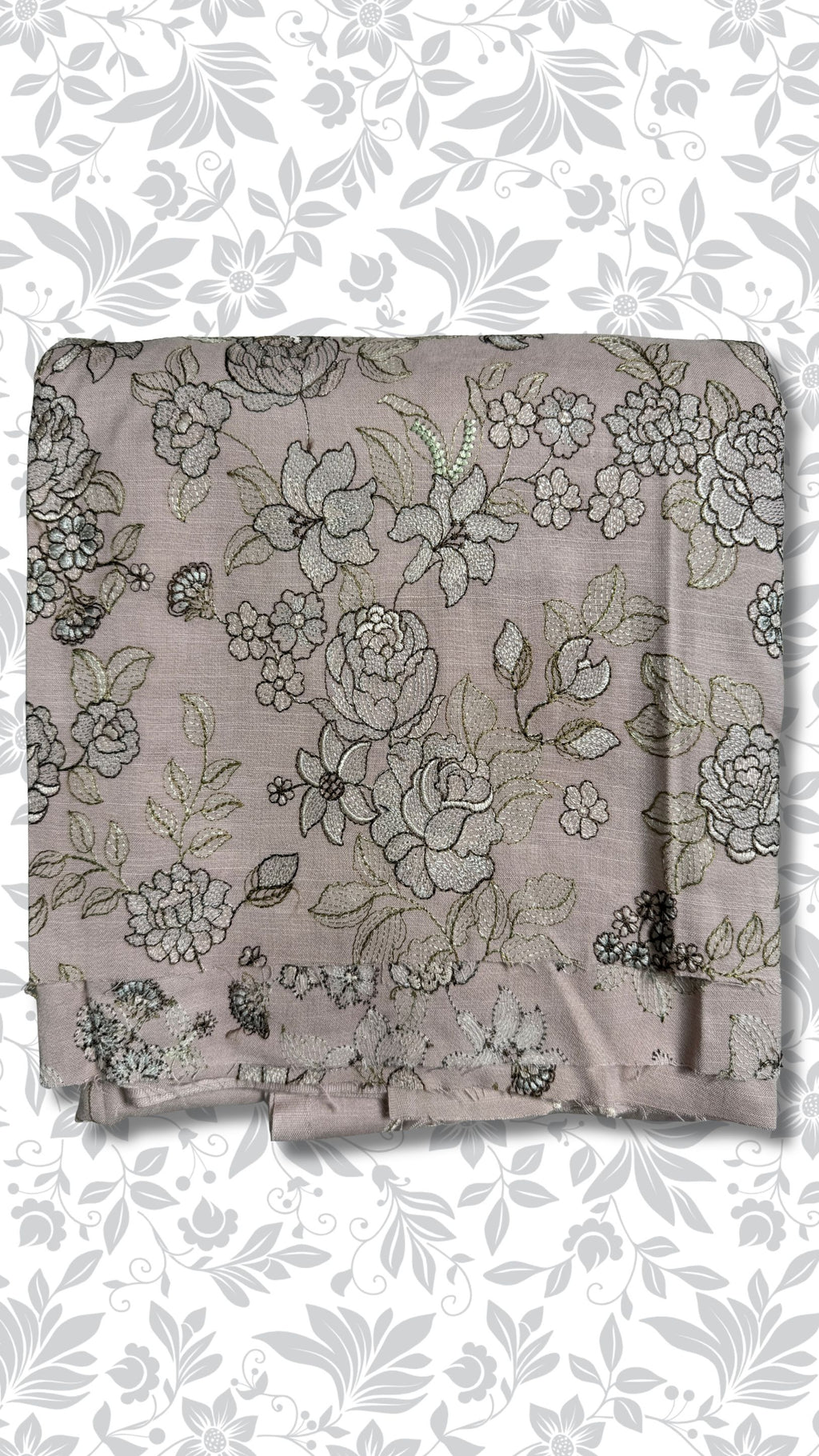 A folded piece of dusty mauve fabric with an intricate floral and vine pattern in black and metallic gold thread, displayed against a white background with a gray floral border.