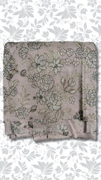 A folded piece of dusty mauve fabric with an intricate floral and vine pattern in black and metallic gold thread, displayed against a white background with a gray floral border.