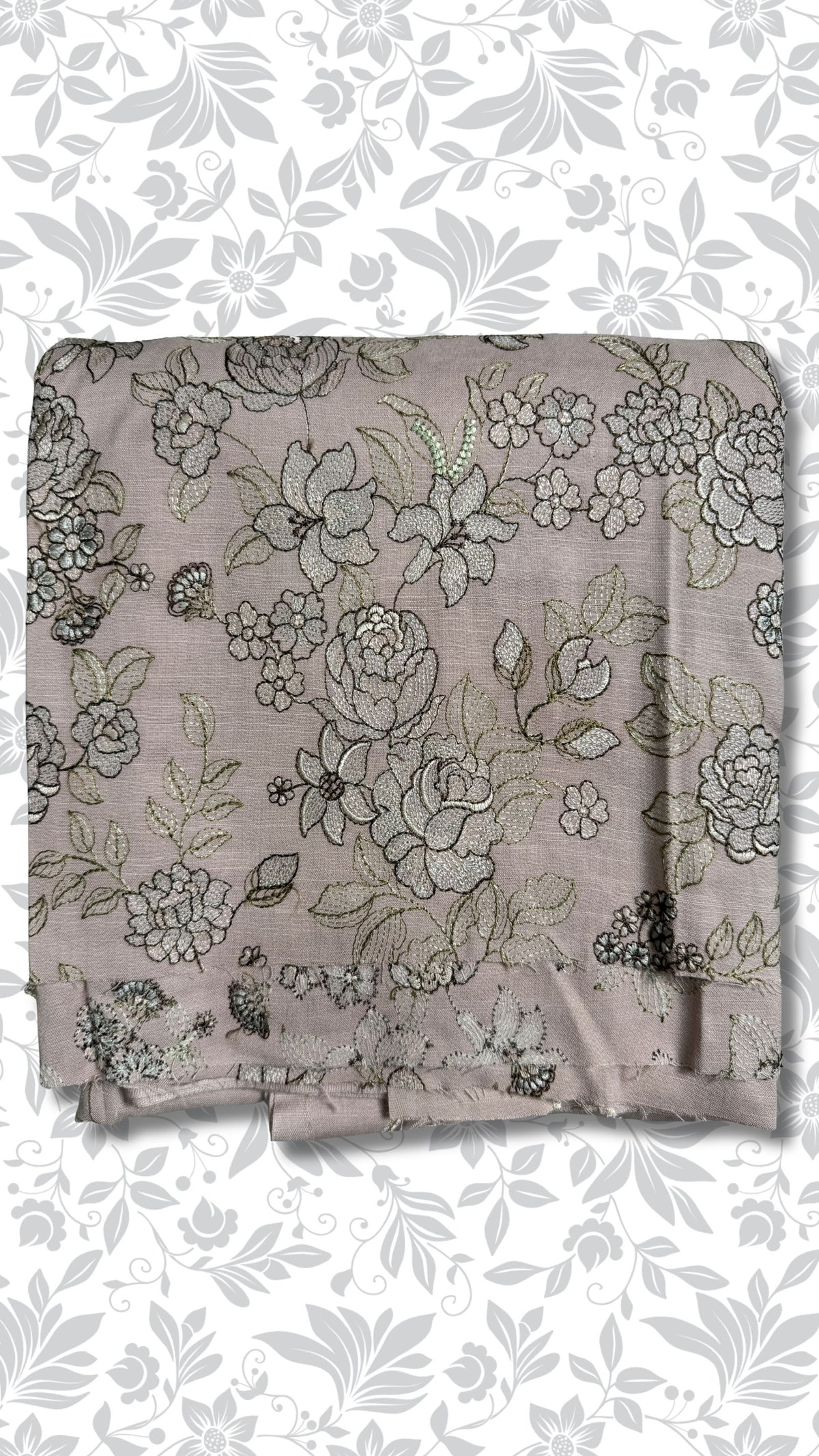 A folded piece of dusty mauve fabric with an intricate floral and vine pattern in black and metallic gold thread, displayed against a white background with a gray floral border.