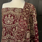 Red fabric with gold embroidery on a mannequin against a dark background