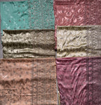 Six folded and laid-out fabric pieces in different colors and textures, including teal, dusty rose, metallic gold, champagne, peach, and mauve, arranged on a gray floor.